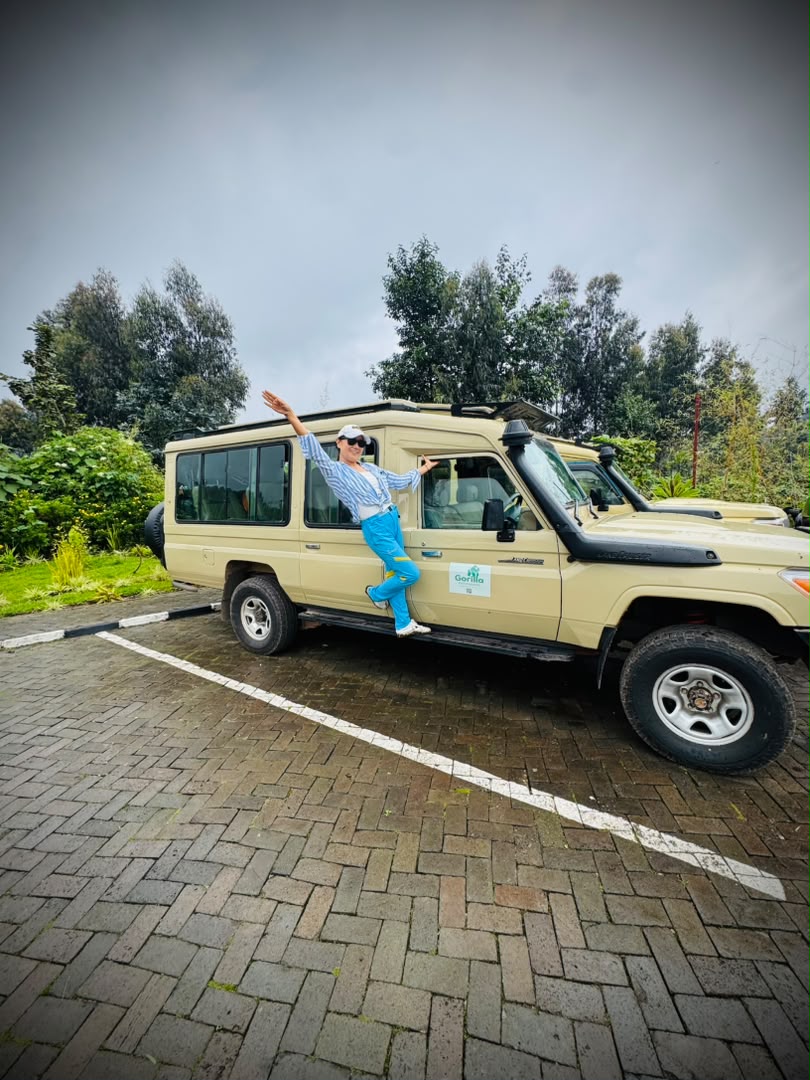 Smiling woman stepping into a beige Gorilla Pathfinders Land Cruiser in a green highland setting