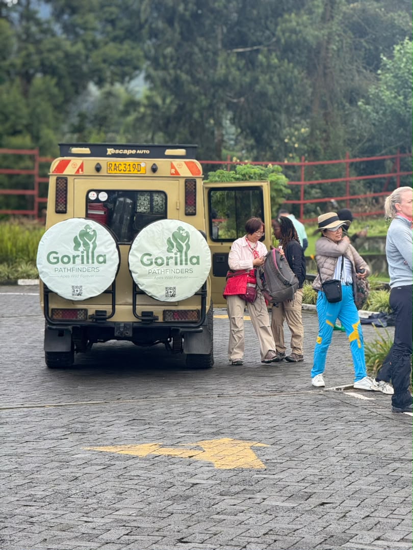 Travellers and guides preparing beside a beige Gorilla Pathfinders vehicle in a parking area