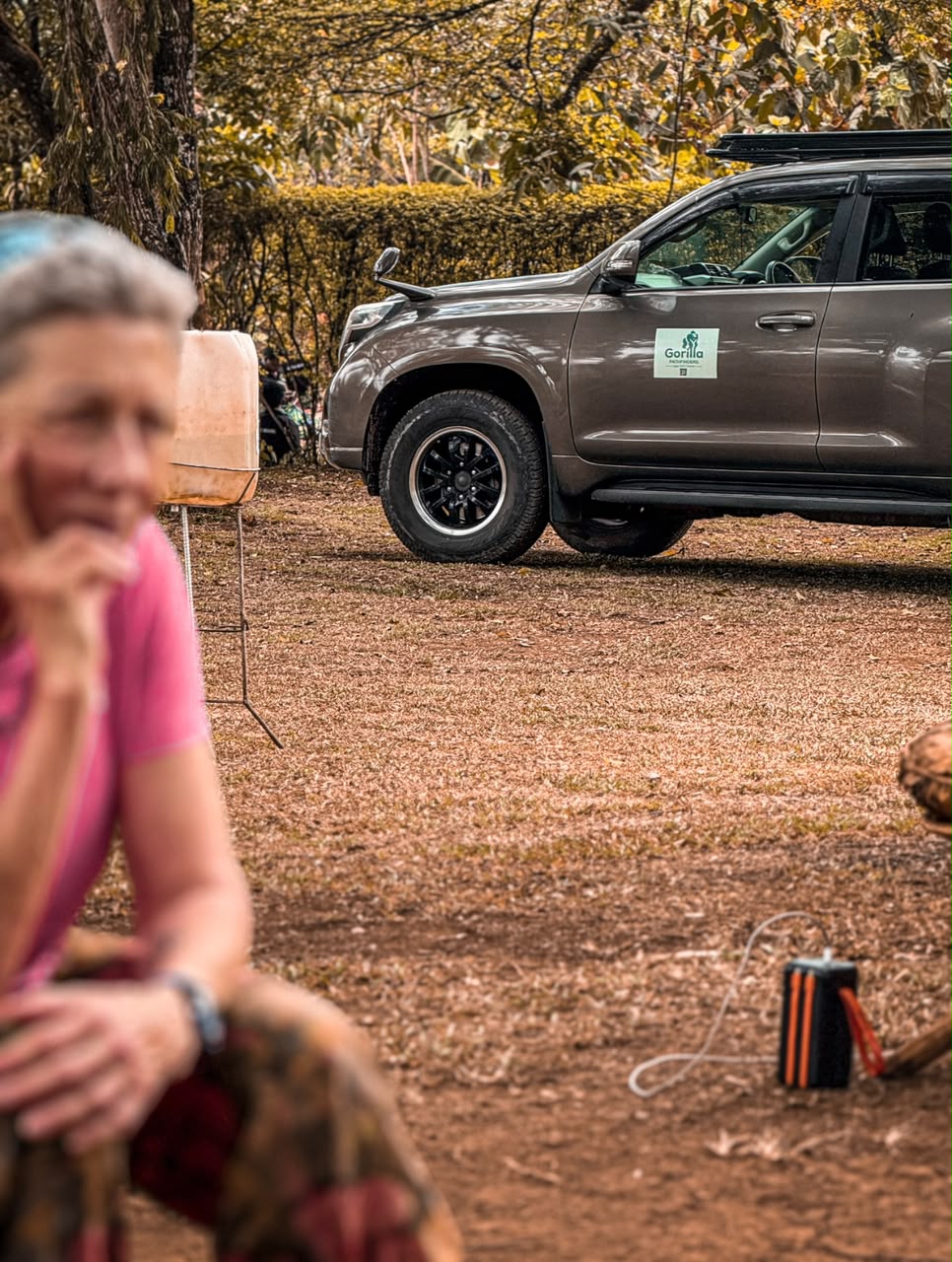 Woman resting outdoors with a grey Gorilla Pathfinders safari vehicle behind her