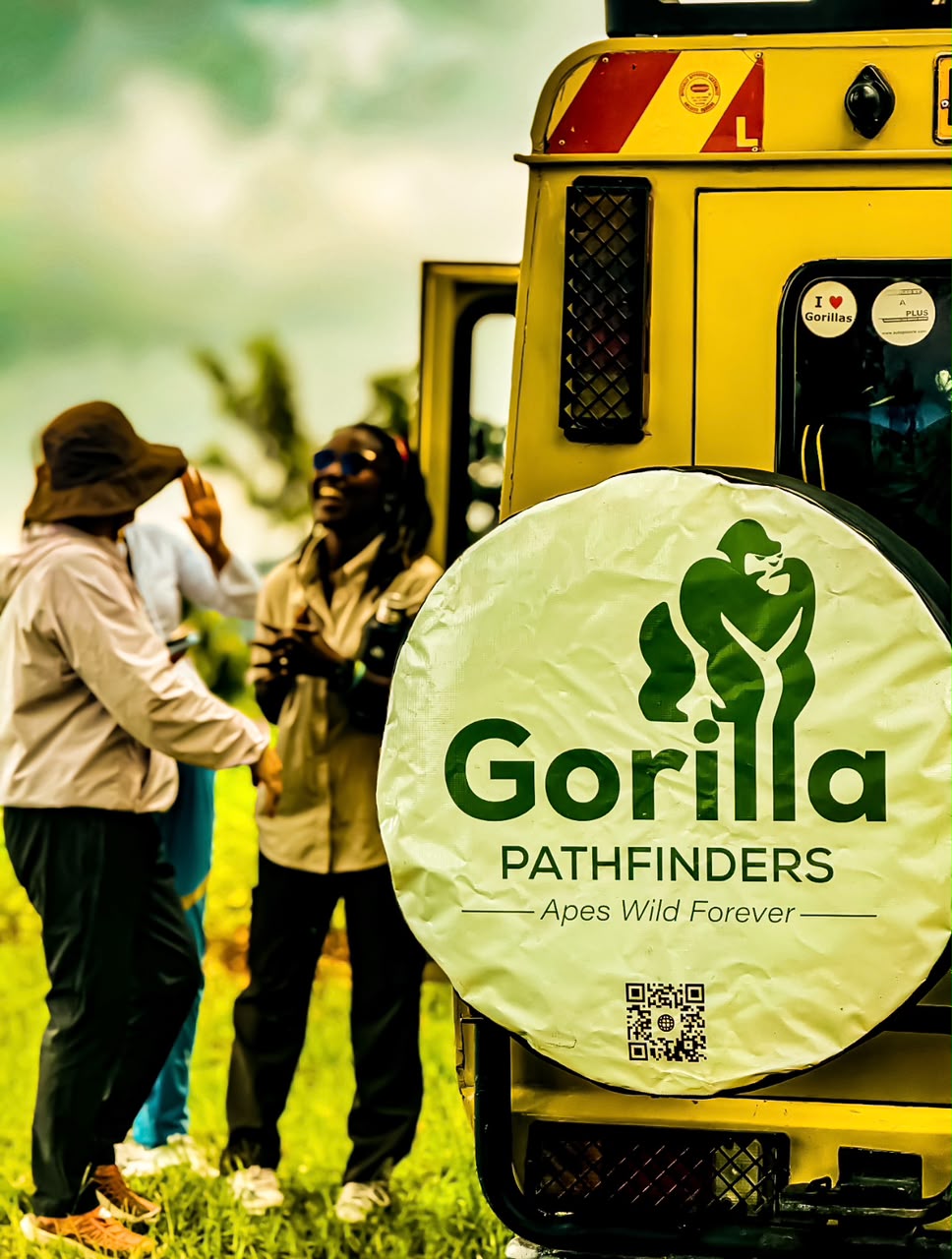 Gorilla Pathfinders spare-wheel cover in focus with travellers and a guide talking behind it