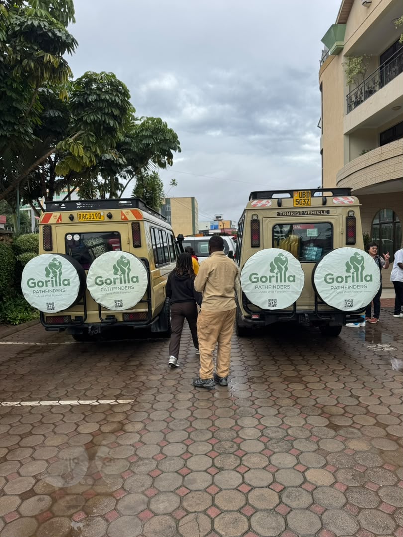 Two Gorilla Pathfinders tourist vehicles parked outside accommodation beneath a cloudy sky