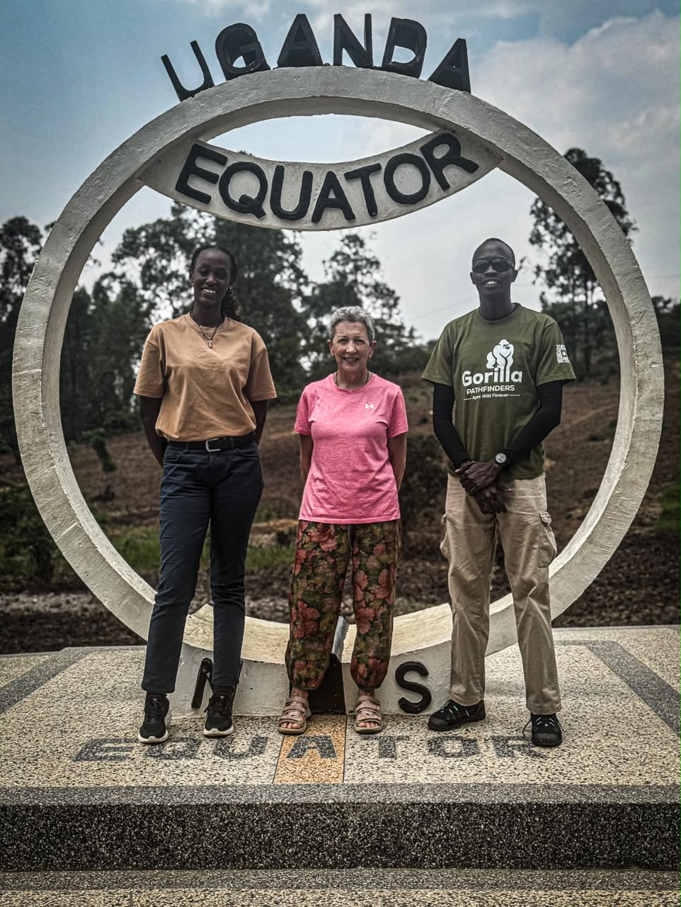 Traveller and two guides posing inside the circular Uganda Equator monument