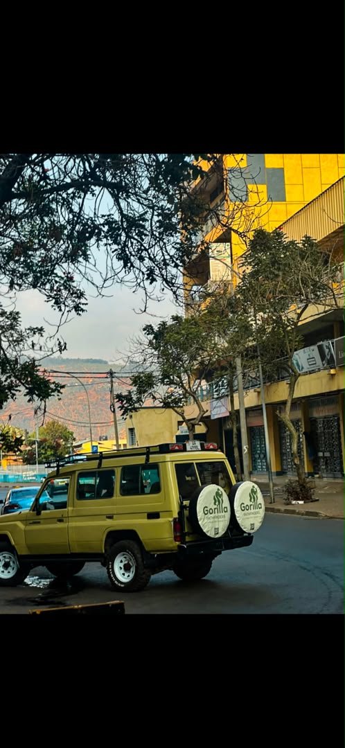 Beige Gorilla Pathfinders safari Land Cruiser driving through an East African city street